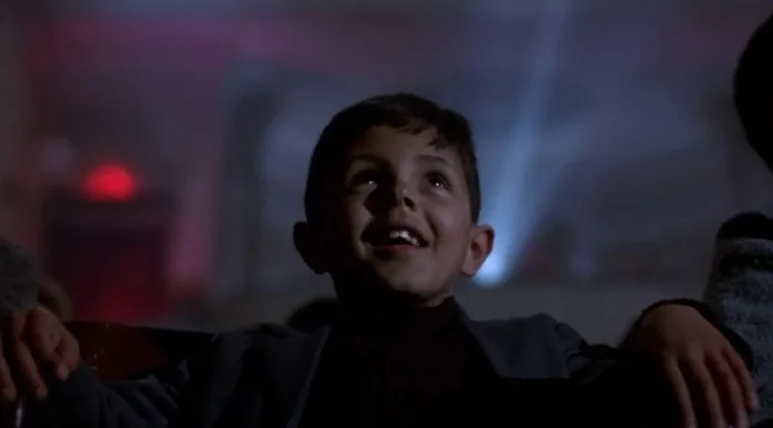 Niño sonriendo frente a la gran pantalla del cine